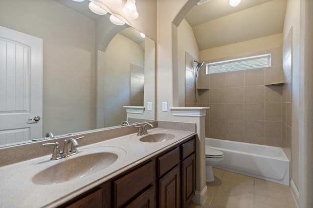 full bath featuring toilet, double vanity, a sink, and tile patterned flooring