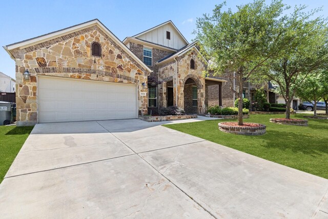 view of front of house featuring driveway, stone siding, board and batten siding, a front yard, and a garage
