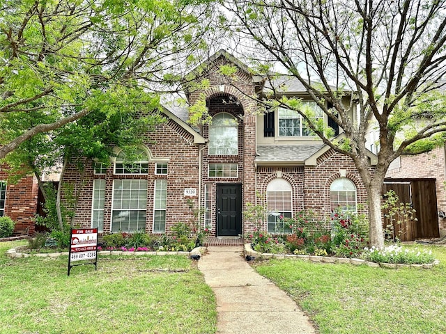 view of front of home featuring brick siding and a front lawn