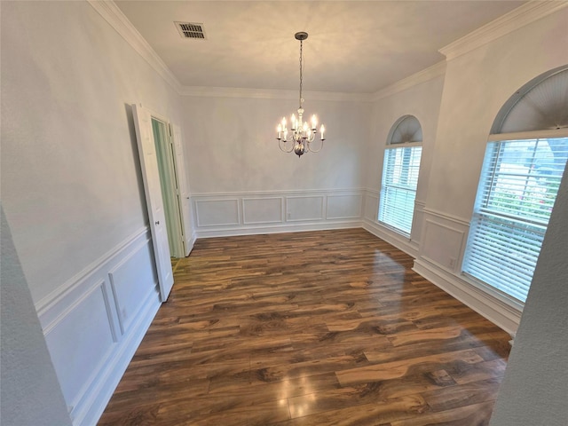 unfurnished dining area featuring a decorative wall, a chandelier, dark wood-style flooring, crown molding, and wainscoting