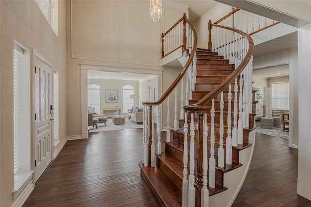 entrance foyer with baseboards, stairs, dark wood-style flooring, and a towering ceiling