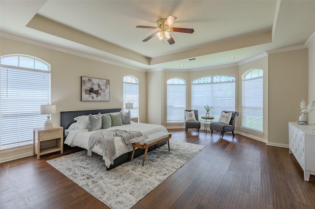 bedroom featuring ornamental molding, a tray ceiling, dark wood finished floors, and multiple windows