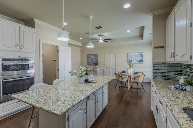 kitchen featuring a center island, ornamental molding, white cabinets, and double oven