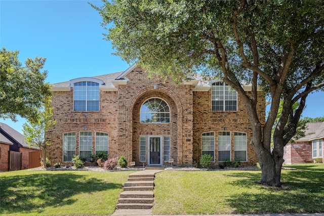traditional-style house with brick siding and a front lawn