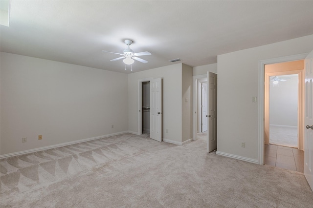 unfurnished bedroom featuring a ceiling fan, visible vents, light colored carpet, and baseboards