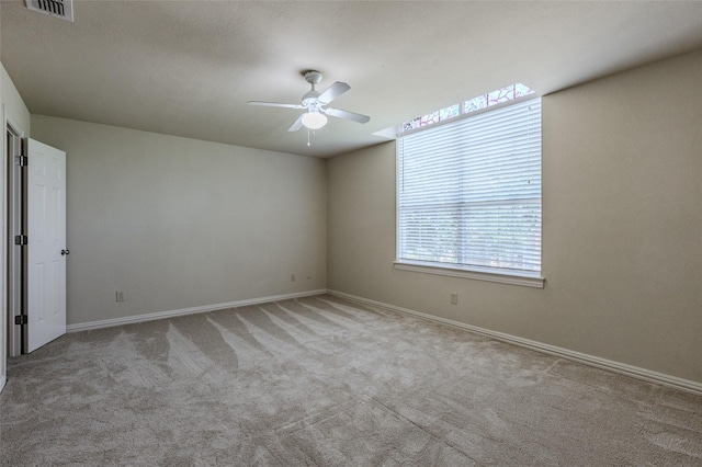carpeted spare room with visible vents, a ceiling fan, and baseboards