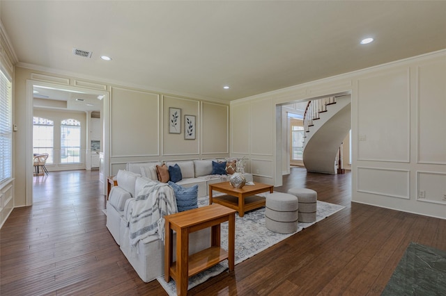 living area with stairway, visible vents, a decorative wall, ornamental molding, and dark wood finished floors
