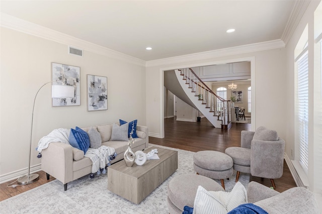 living area with wood finished floors, stairs, baseboards, a notable chandelier, and crown molding