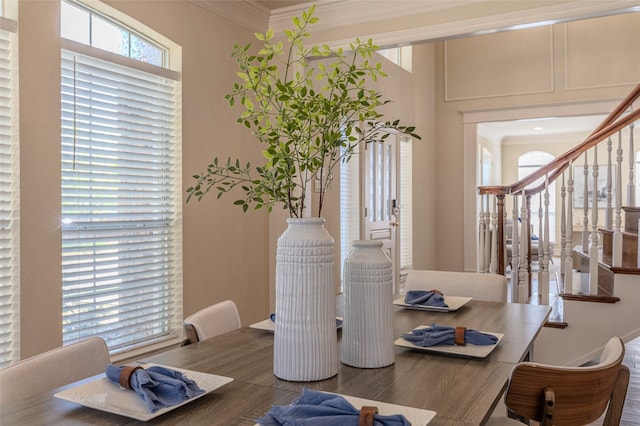 dining space with wood finished floors, crown molding, and stairs