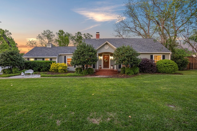 ranch-style house featuring fence, a chimney, roof with shingles, and a front yard