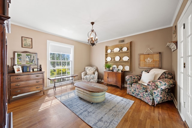 sitting room featuring light wood-type flooring, visible vents, a notable chandelier, and ornamental molding