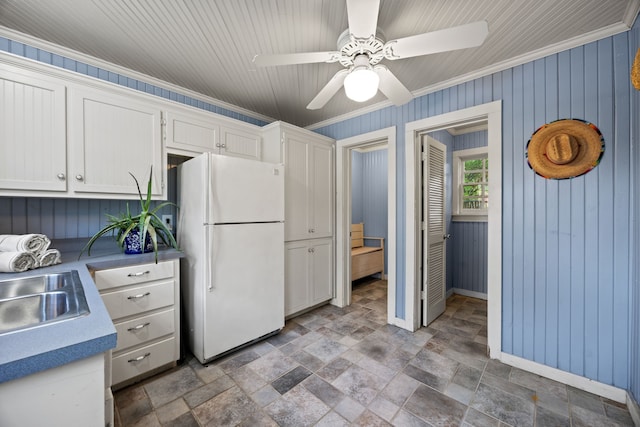 kitchen featuring stone finish floor, a sink, freestanding refrigerator, baseboards, and ceiling fan