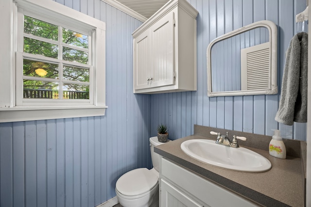 bathroom featuring wooden walls, vanity, and toilet
