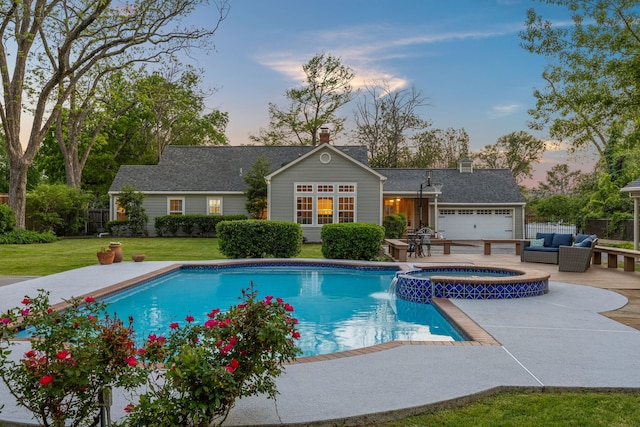 pool at dusk featuring fence, outdoor lounge area, a patio area, a yard, and a pool with connected hot tub