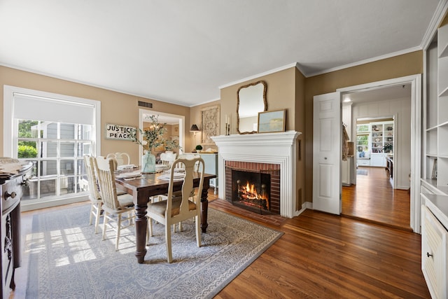 dining space with visible vents, plenty of natural light, a brick fireplace, and wood finished floors