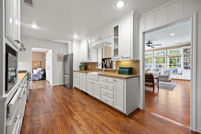 kitchen featuring a sink, dark wood finished floors, freestanding refrigerator, visible vents, and glass insert cabinets
