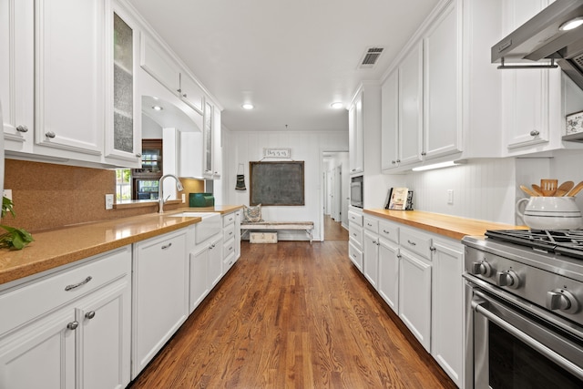 kitchen with stainless steel gas stove, visible vents, a sink, glass insert cabinets, and white cabinetry