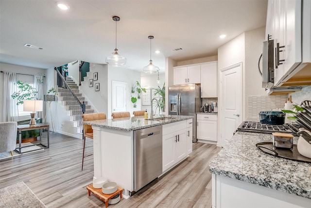kitchen featuring recessed lighting, light wood-style flooring, visible vents, a breakfast bar area, and stainless steel appliances