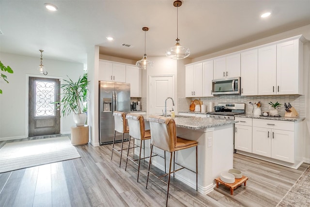 kitchen with tasteful backsplash, visible vents, appliances with stainless steel finishes, a sink, and light wood finished floors