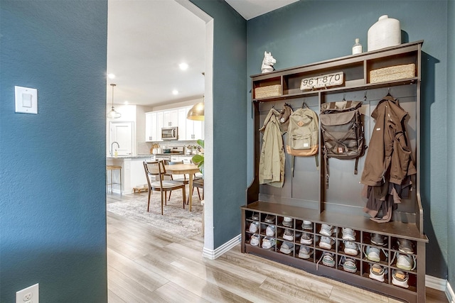 mudroom featuring light wood-style floors, recessed lighting, a sink, a textured wall, and baseboards