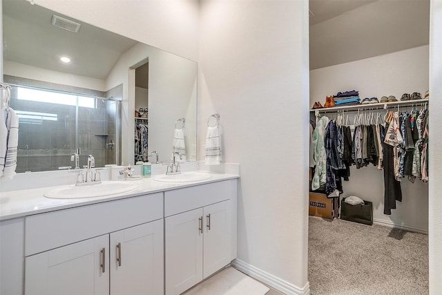 bathroom with a stall shower, double vanity, a sink, and visible vents