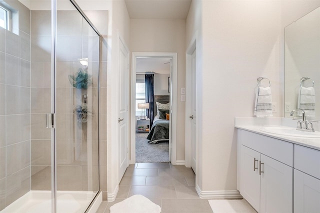 ensuite bathroom featuring ensuite bathroom, a shower stall, vanity, tile patterned flooring, and baseboards
