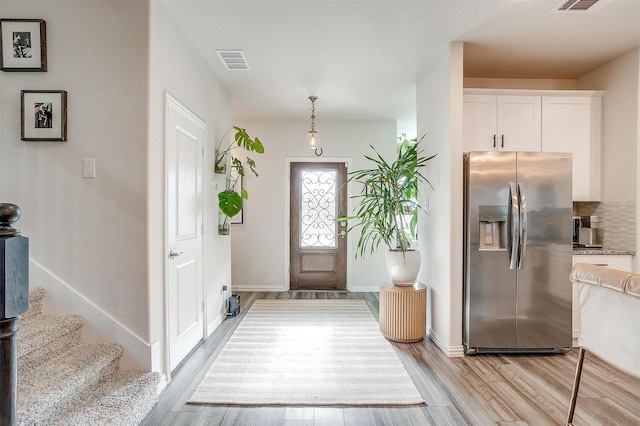 foyer entrance with light wood-style floors, baseboards, and visible vents