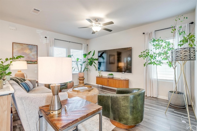 living area with light wood finished floors, visible vents, baseboards, and a ceiling fan
