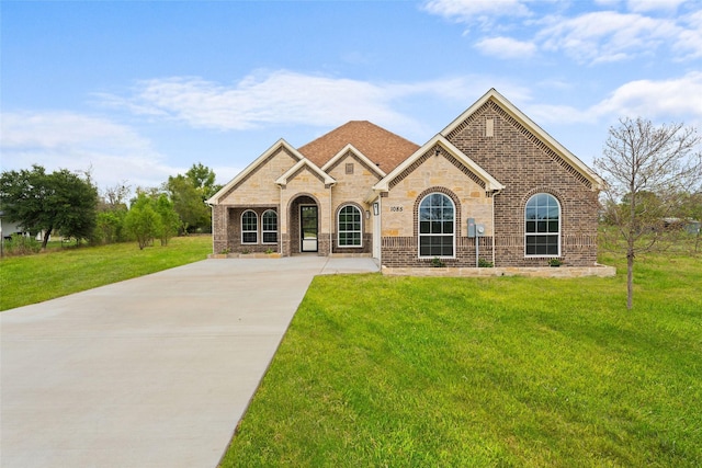 view of front of home featuring driveway, a front lawn, and brick siding