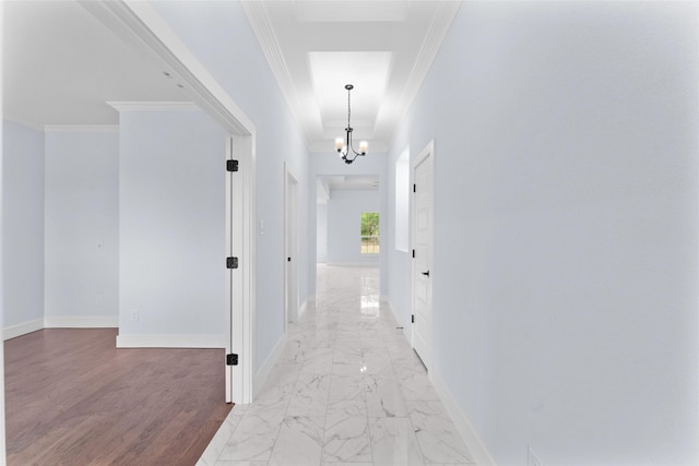 corridor with a chandelier, marble finish floor, baseboards, and crown molding