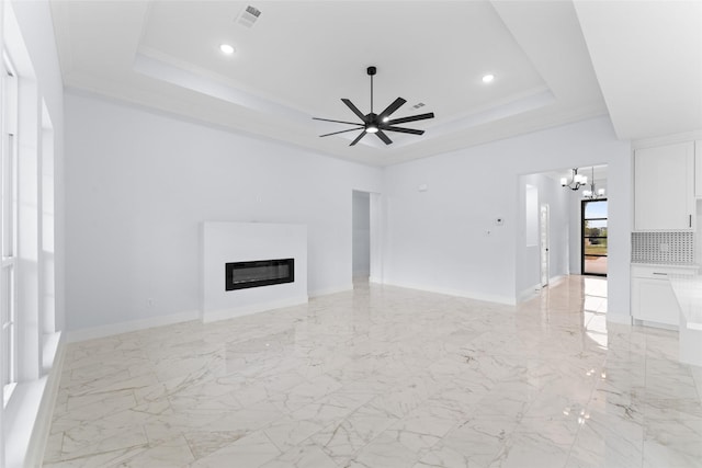 unfurnished living room featuring ceiling fan with notable chandelier, a glass covered fireplace, visible vents, recessed lighting, and a raised ceiling