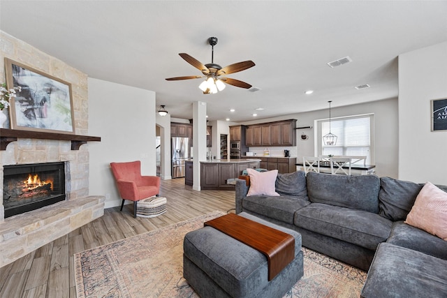 living room with light wood finished floors, recessed lighting, a fireplace, ceiling fan, and visible vents