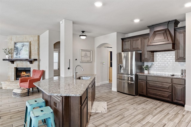 kitchen with appliances with stainless steel finishes, premium range hood, arched walkways, and a sink