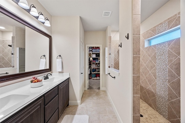 full bath featuring a sink, double vanity, visible vents, a walk in closet, and walk in shower
