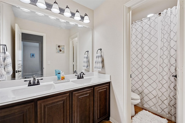 bathroom featuring toilet, double vanity, a sink, and a shower with shower curtain