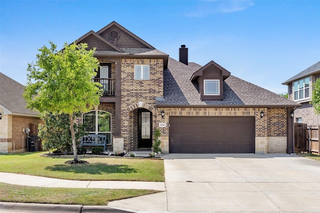 view of front of house featuring concrete driveway, a balcony, an attached garage, brick siding, and a front lawn