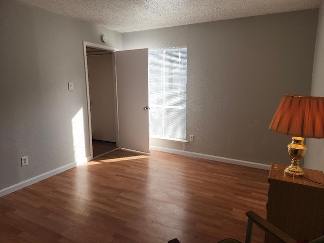 4614 Country Creek Dr Unit 1167, Dallas, TX 75236 - empty room with a textured wall, baseboards, wood finished floors, and a textured ceiling