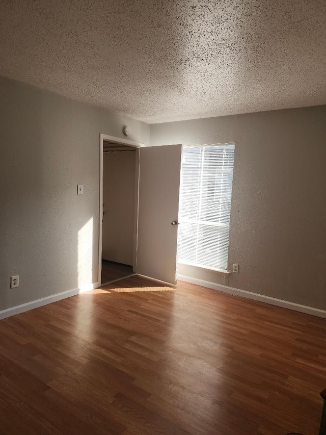 4614 Country Creek Dr Unit 1167, Dallas, TX 75236 - empty room with wood finished floors, a textured ceiling, baseboards, and a textured wall
