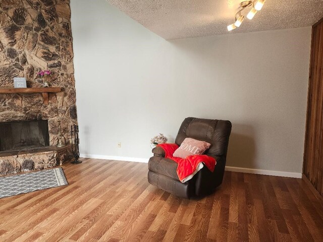 4614 Country Creek Dr Unit 1167, Dallas, TX 75236 - living area featuring baseboards, a stone fireplace, wood finished floors, and a textured ceiling
