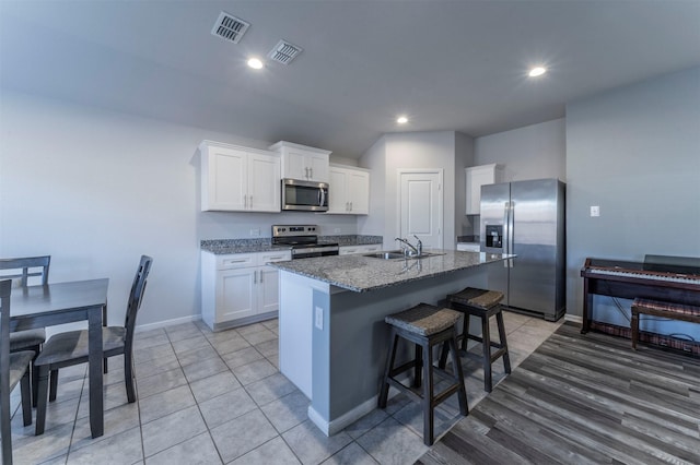 kitchen featuring a sink, visible vents, appliances with stainless steel finishes, and an island with sink