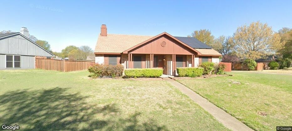 view of front of home with solar panels, a chimney, fence, and a front lawn