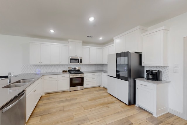 2812 Bluejack Rd, Mckinney, TX 75071 - kitchen featuring stainless steel appliances, backsplash, white cabinets, light wood-style floors, and a peninsula