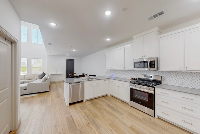 2812 Bluejack Rd, Mckinney, TX 75071 - kitchen featuring appliances with stainless steel finishes, decorative backsplash, open floor plan, a peninsula, and white cabinetry