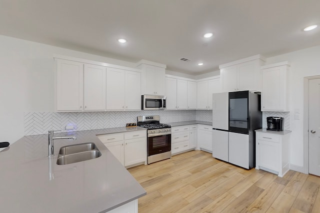 2812 Bluejack Rd, Mckinney, TX 75071 - kitchen with appliances with stainless steel finishes, decorative backsplash, white cabinets, light wood-style flooring, and recessed lighting