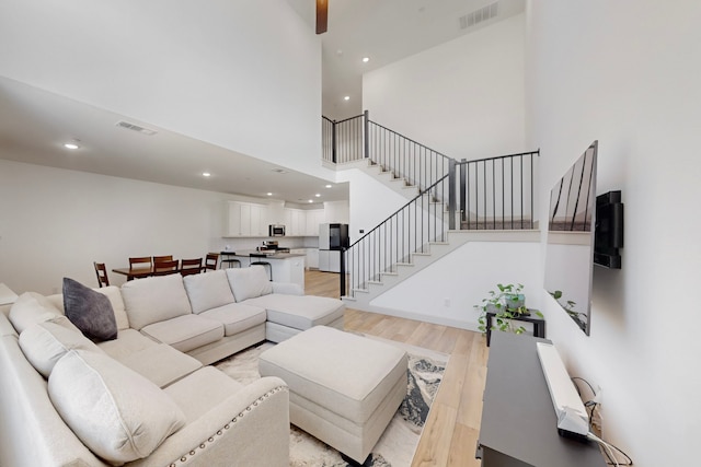 2812 Bluejack Rd, Mckinney, TX 75071 - living room with light wood-type flooring, stairs, recessed lighting, and a towering ceiling