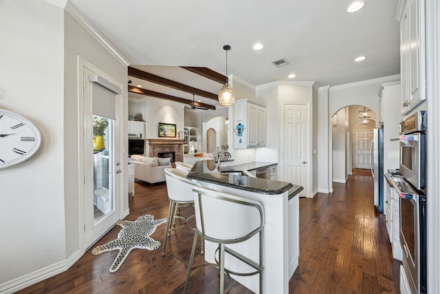 1318 Amsterdam Ct, Granbury, TX 76048 - kitchen with arched walkways, appliances with stainless steel finishes, a peninsula, open floor plan, and recessed lighting