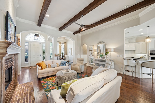 1318 Amsterdam Ct, Granbury, TX 76048 - living area featuring arched walkways, beam ceiling, a ceiling fan, dark wood finished floors, and a fireplace