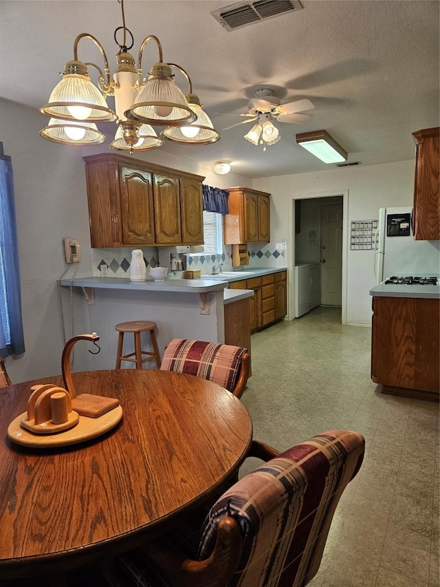 dining space with visible vents, a ceiling fan, light floors, and washer / clothes dryer