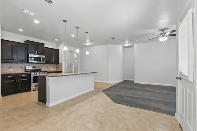 kitchen with tasteful backsplash, ceiling fan, a kitchen island with sink, recessed lighting, and stainless steel appliances