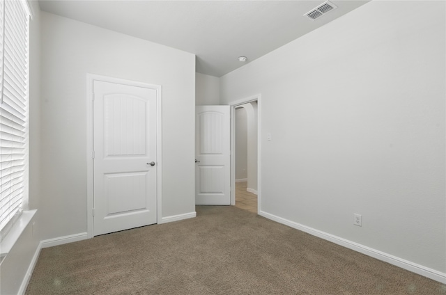 unfurnished bedroom with carpet flooring, visible vents, and baseboards